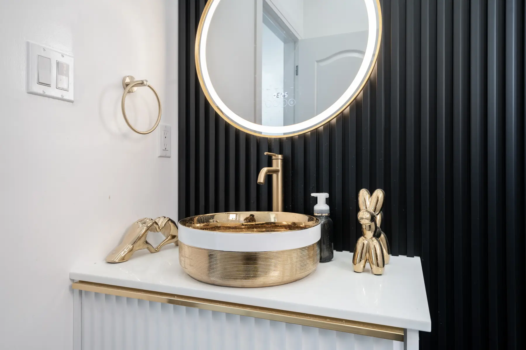 Custom fluted vanity with gold accents and illuminated round mirror