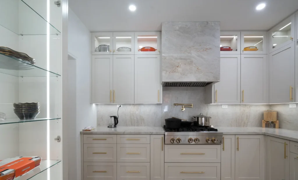 Custom kitchen cabinetry with brass hardware and illuminated glass shelving