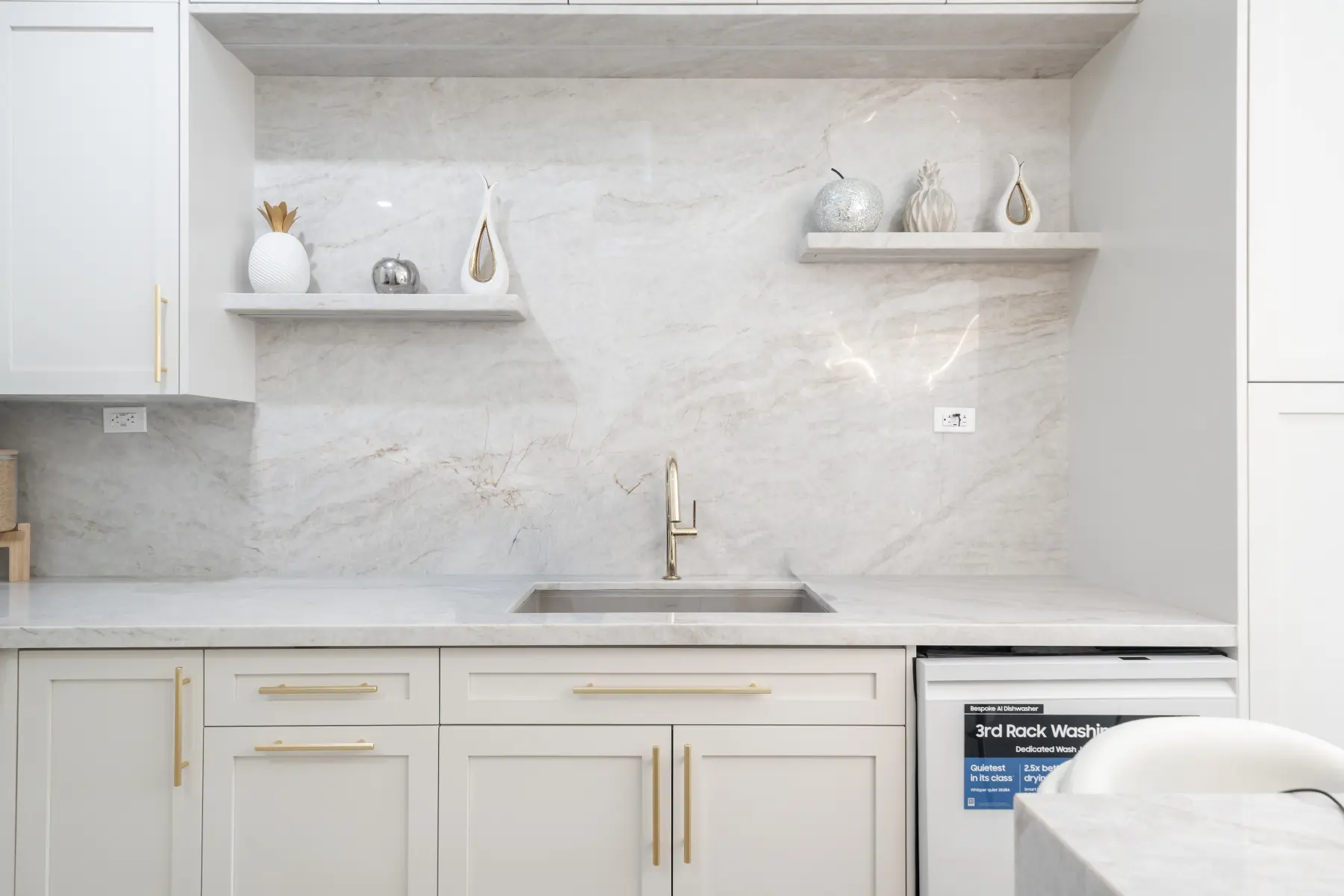 Custom kitchen cabinetry with marble backsplash, floating shelves and brass hardware